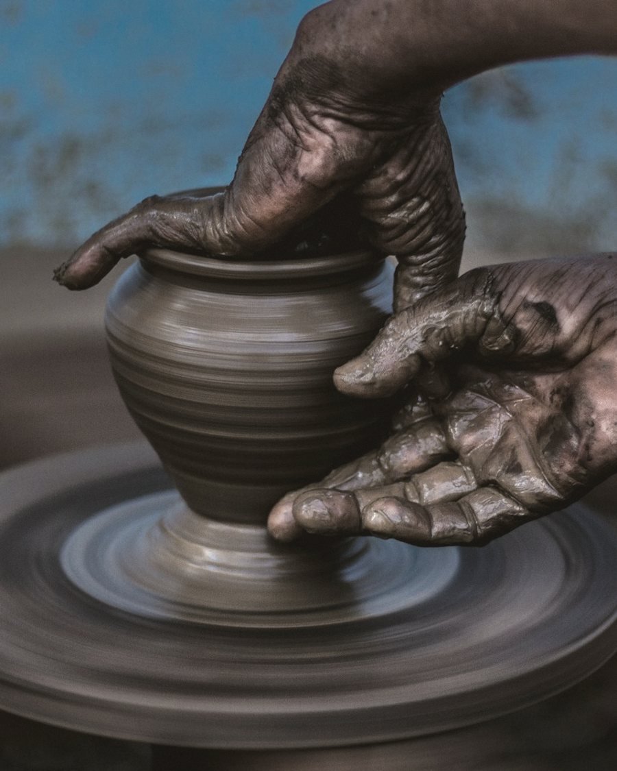 Hands shaping a stoneware vessel on the wheel